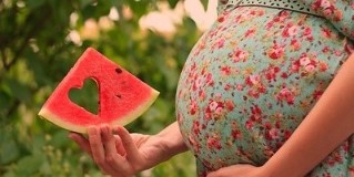 plátok melónu v ruke tehotnej ženy